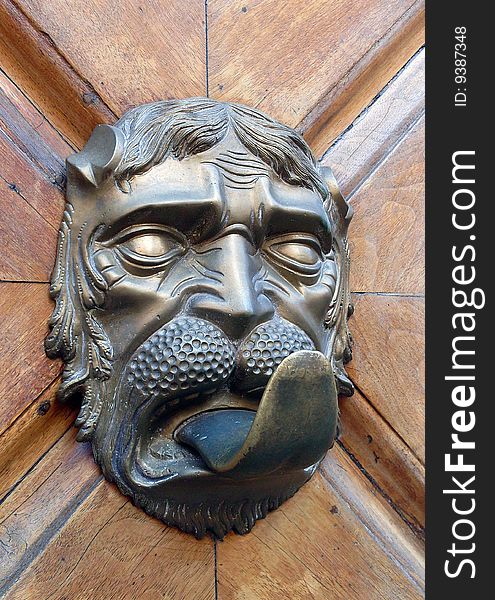 Old strange door handle: a human face with long tongue