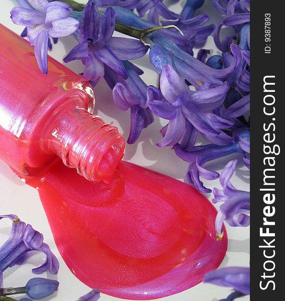 Spilled pink nail polish and purple flowers