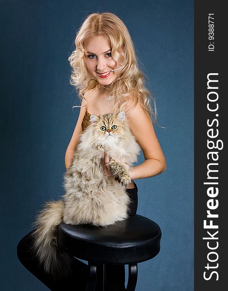 Beautiful blonde smiling woman with fluffy cat over dark background