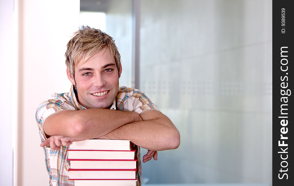 Portrait of male student leaning on books.