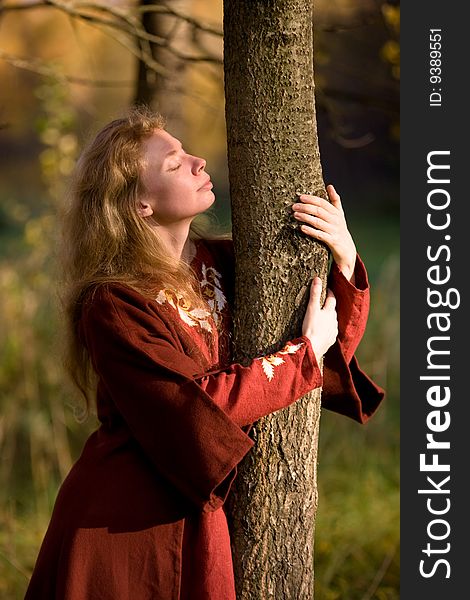 The blonde girl in medieval red dress in the autumn forest. The blonde girl in medieval red dress in the autumn forest