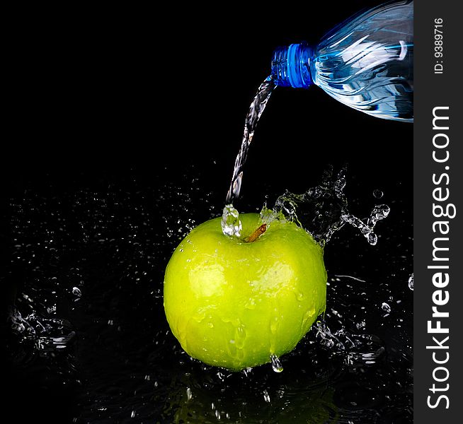 Fresh water splash on green apple on black background