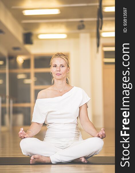 Beautiful Young Woman Sitting In Lotos Pose And Practicing Meditation In Yoga Hall