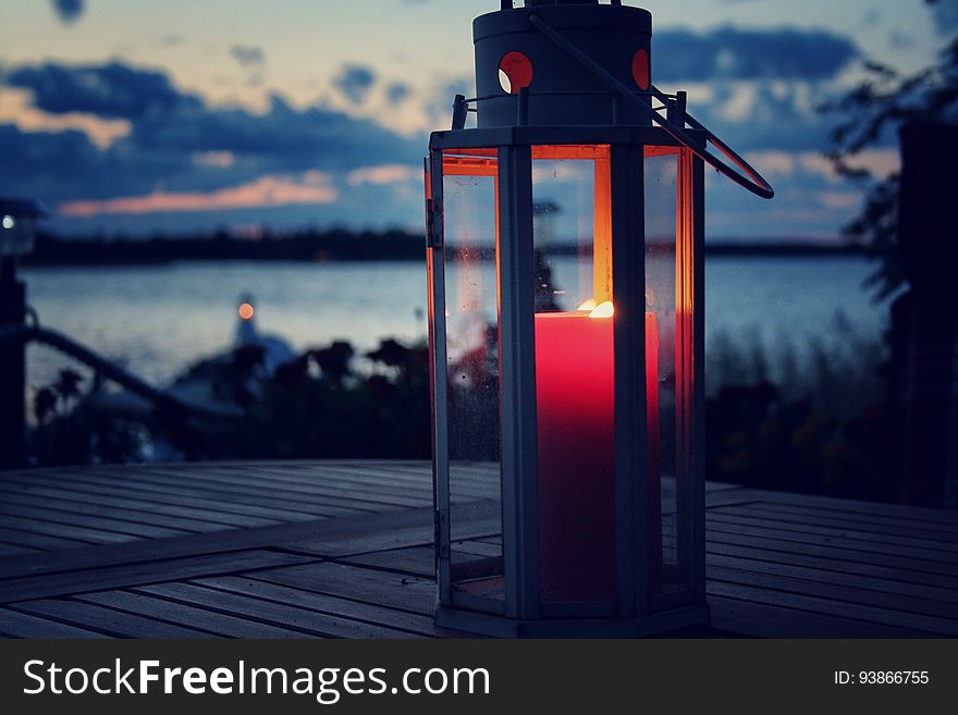 Candle lit lantern next to a beach.