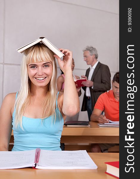 Portrait of female student holding book on head.