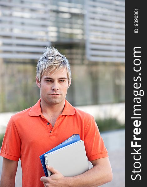 Portrait of male student holding files.