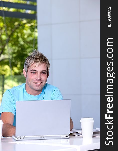 Portrait of male student working on laptop.