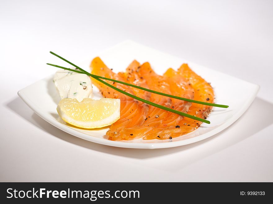Salmon with cheese and lemon on a white plate. Salmon with cheese and lemon on a white plate
