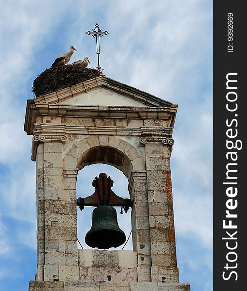 Storks couple close to a church bell