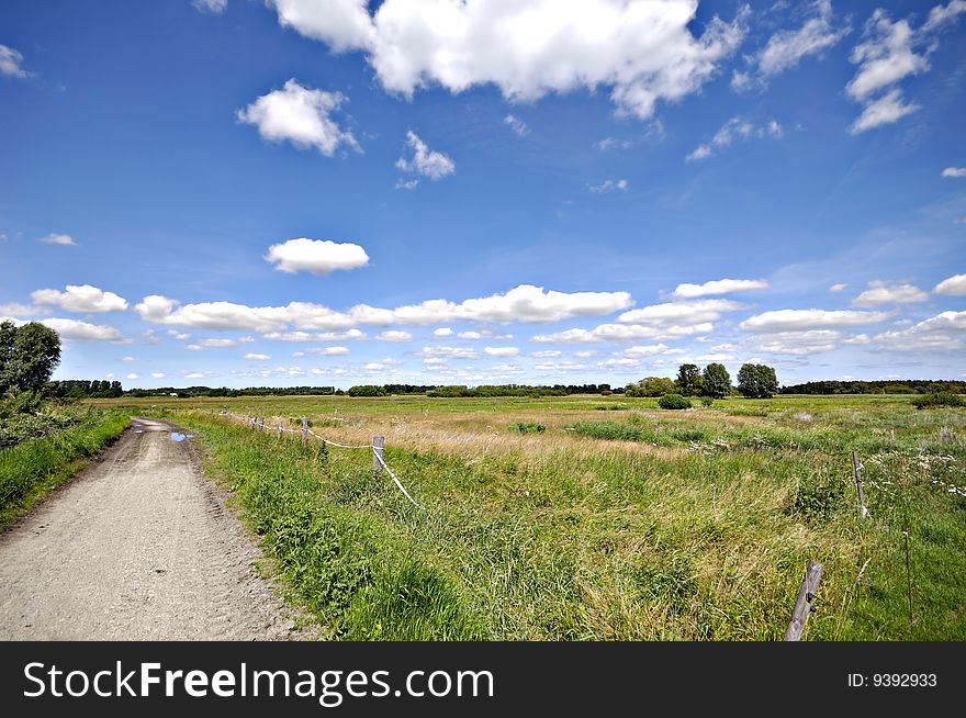 Path and green landscape with blue and cloudy sky. Path and green landscape with blue and cloudy sky