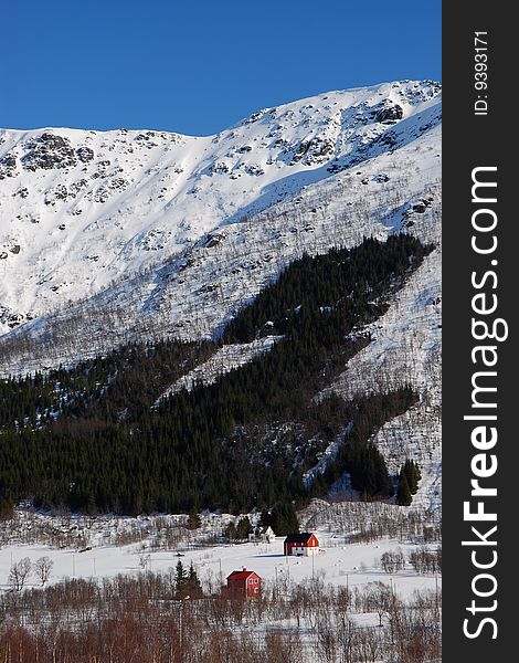 A small farm set in a mountainous winter landscape.