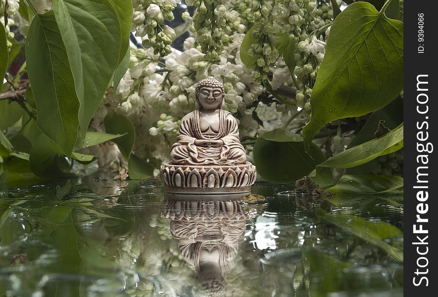 Small buddha statue under branches of blooming tree. Small buddha statue under branches of blooming tree