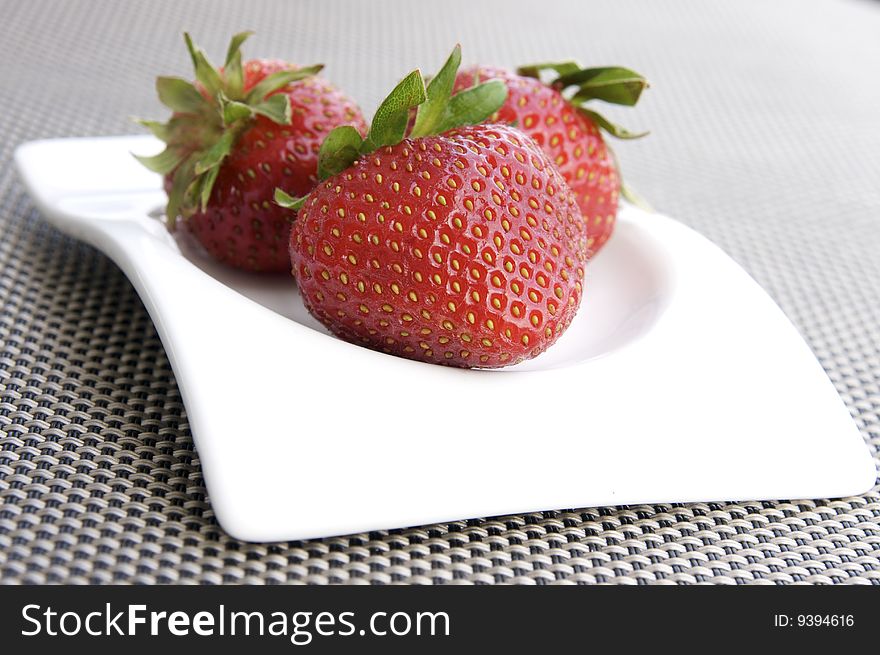 Three ripe strawberries on a white plate. Three ripe strawberries on a white plate