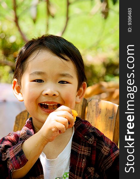 A picture of a little chinese boy eating loquat and enjoying it greatly