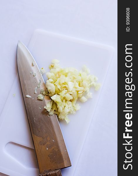 White onion minced by a chef's knife on a cutting board. White onion minced by a chef's knife on a cutting board