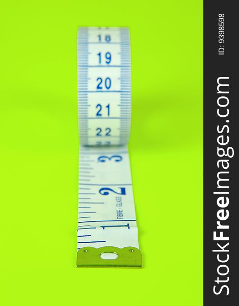 A measuring tape isolated against a lime green background. A measuring tape isolated against a lime green background