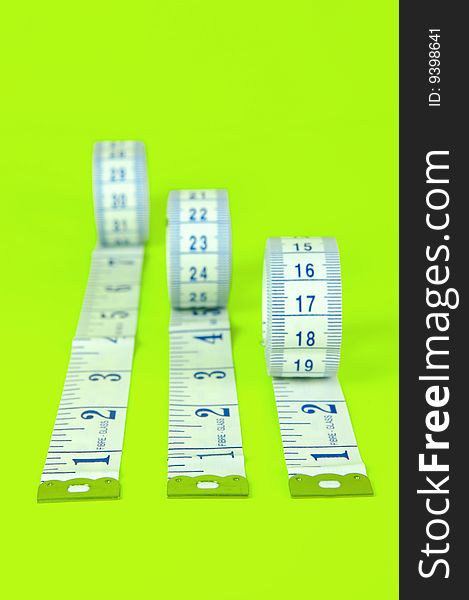 A measuring tape isolated against a lime green background. A measuring tape isolated against a lime green background