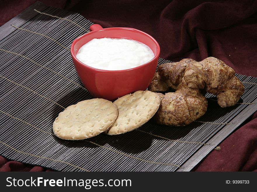 Yoghourt and croissants, biscuits isolated on dark background