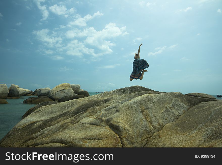 Jumping girl over stone beach background