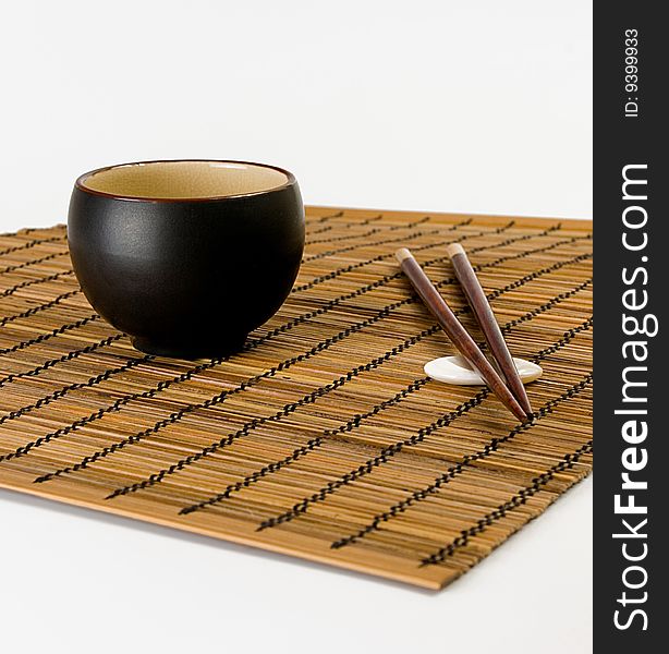 Bowl and chopsticks on bamboo serviette