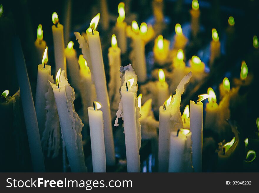 Candles lit at night, detail of an element of light, beliefs and faith, flame