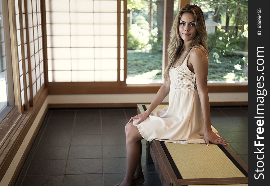 A woman sitting on a bench in a house with paper walls. A woman sitting on a bench in a house with paper walls.