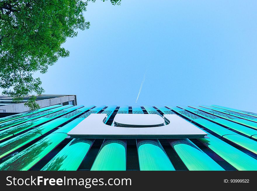 Front of modern green building with logo against blue skies on sunny day. Front of modern green building with logo against blue skies on sunny day.