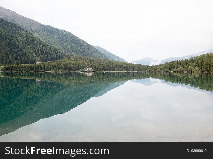 Lake in countryside with pine tree forest on hillside shores on sunny day. Lake in countryside with pine tree forest on hillside shores on sunny day.