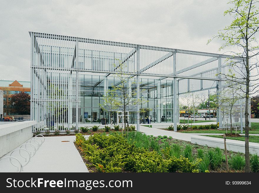 Exterior of glass and steel modern building with landscaping on sunny day.