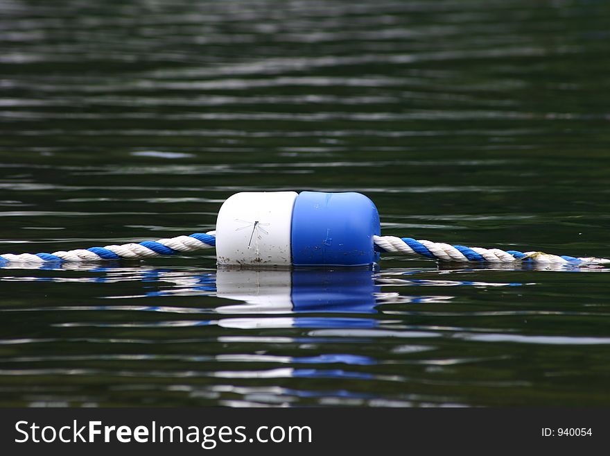 A buoy and rope seperate the open lake and the swimming area. A buoy and rope seperate the open lake and the swimming area