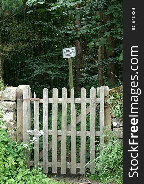 Old broken wooden gate leads to a path thorough the wood but the sign stictly private wards off any unwelcome person. Old broken wooden gate leads to a path thorough the wood but the sign stictly private wards off any unwelcome person