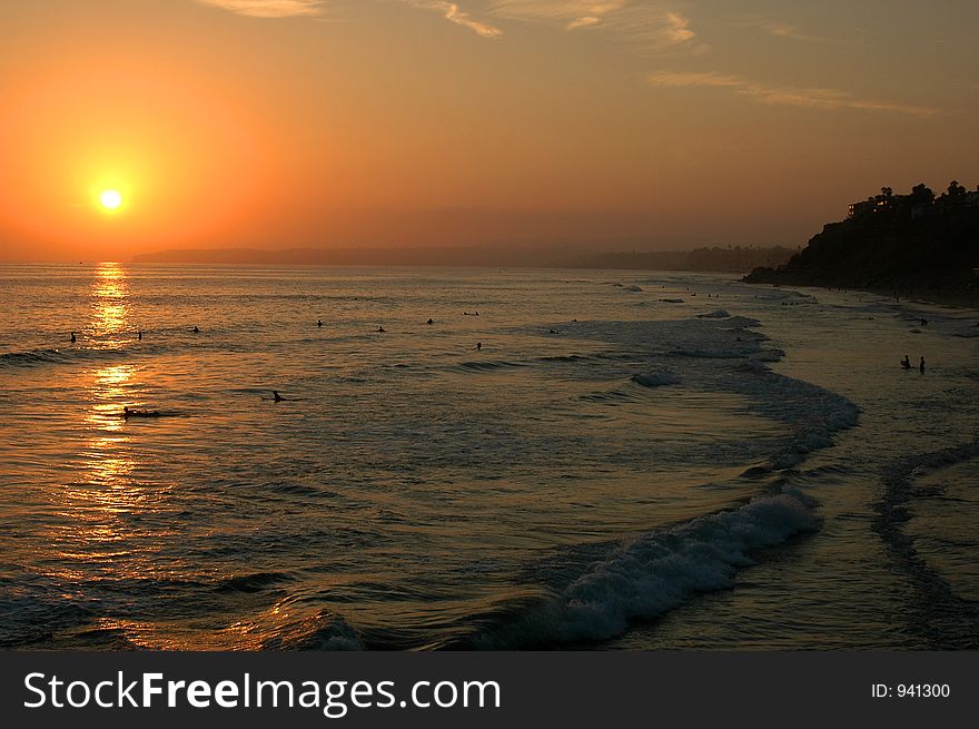 Beautiful sunset on the ocean, people swimming, enjoying warm water. Beautiful sunset on the ocean, people swimming, enjoying warm water