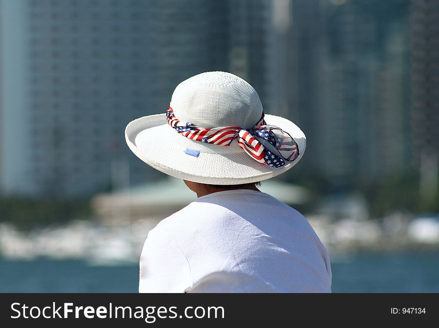 Woman sitting alone on sea wall enjoying the ocean breeze and view of city. Woman sitting alone on sea wall enjoying the ocean breeze and view of city.