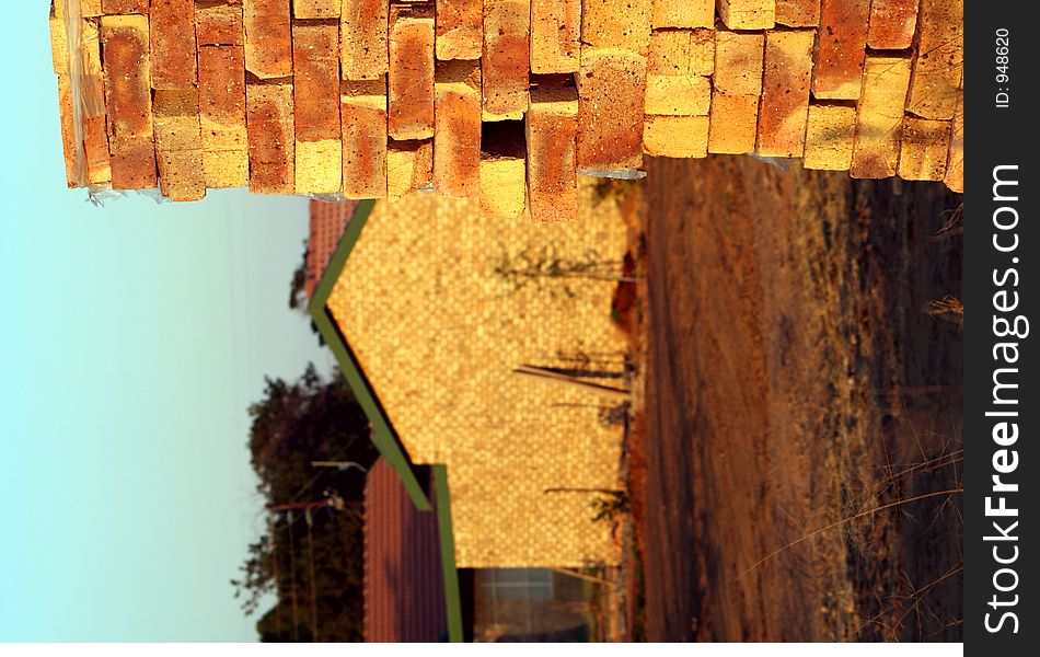 Close up of a pile of brinks on a building site, with completed home in the background