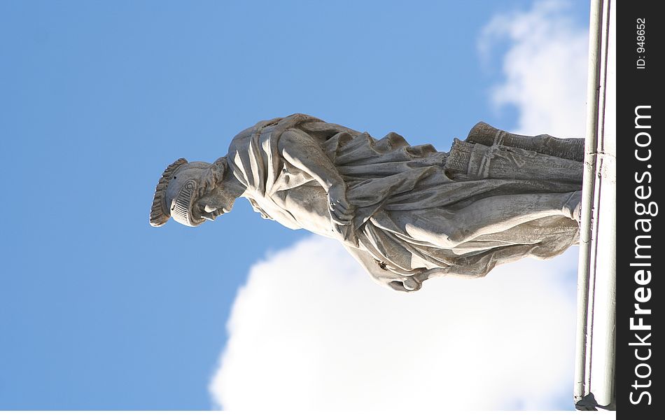 Roman statue n a roof with white clouds in the background. Roman statue n a roof with white clouds in the background.