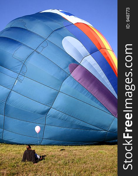 Colorful Hot Air Balloon on Ground with Father and Daughter sitting and Watching