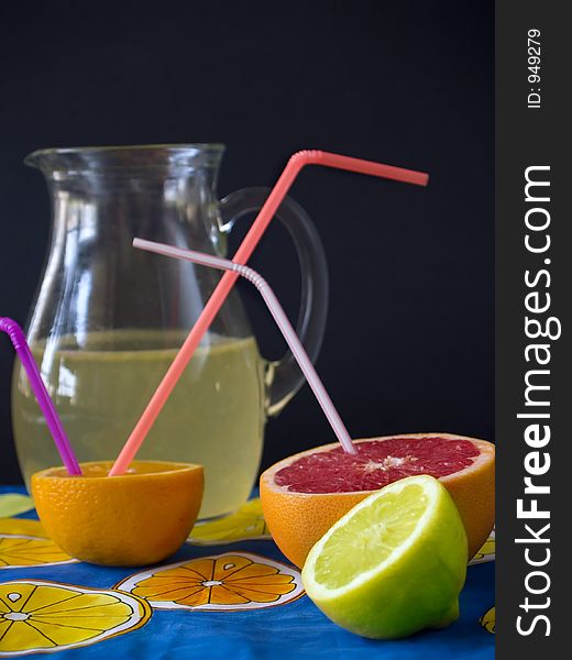 Fresh fruits and lemonade at jug, black background