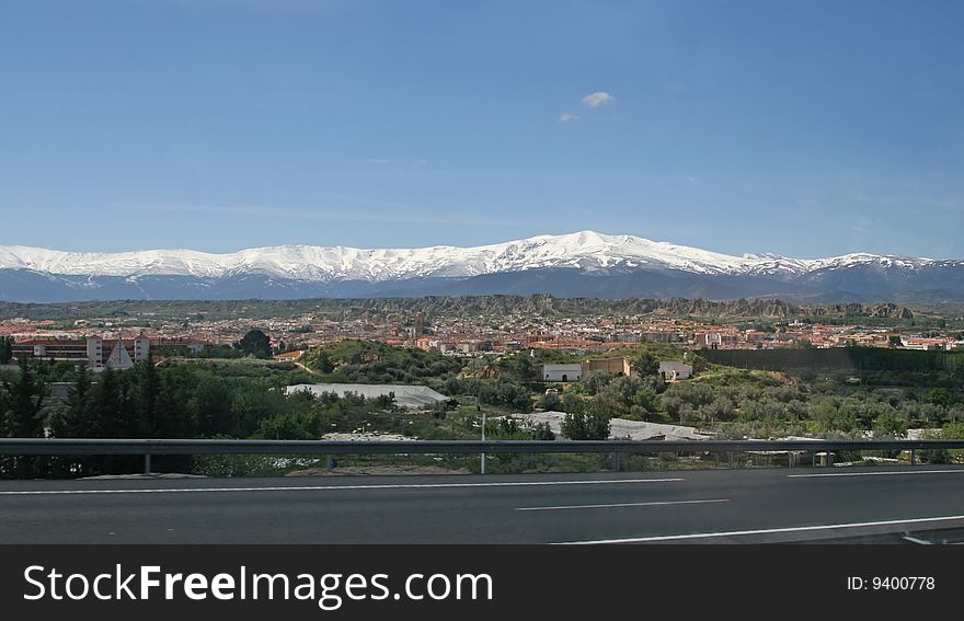 The mountains covered with snow and a valley in green trees. The mountains covered with snow and a valley in green trees