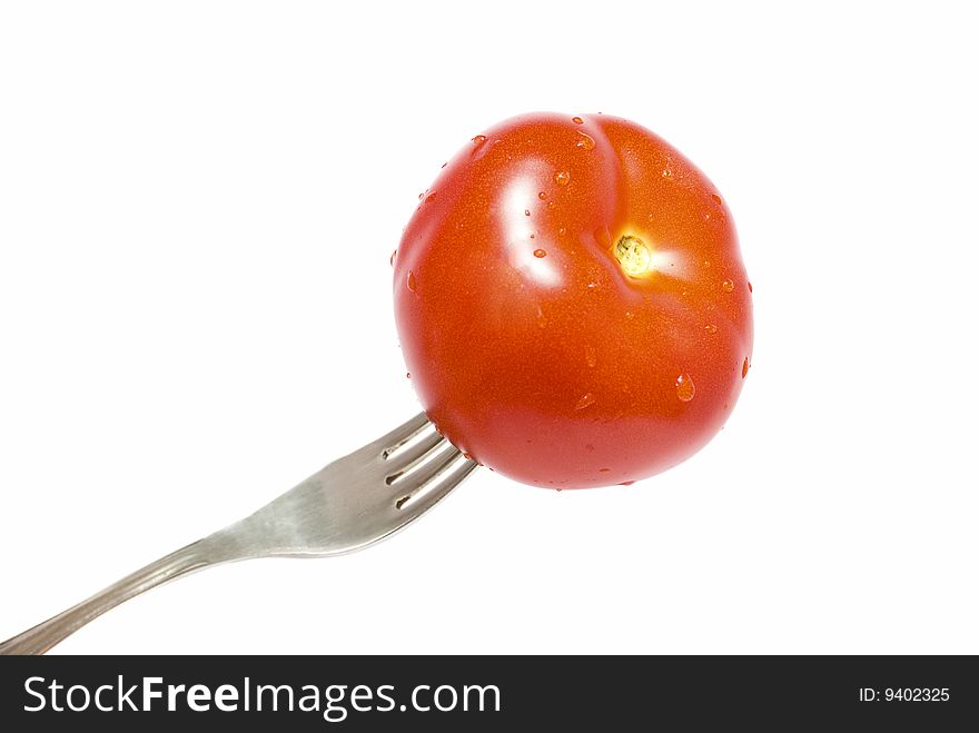 Red tomato on the stainless fork isolated. Red tomato on the stainless fork isolated