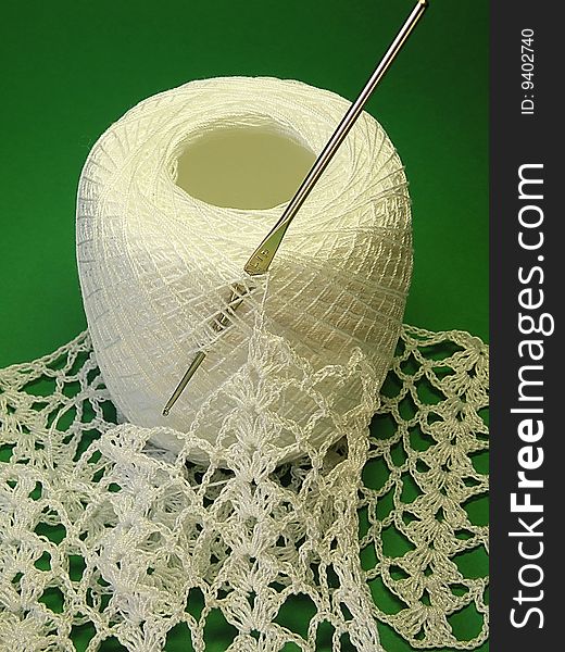 White crochet, bundle yarn and hook on the green background