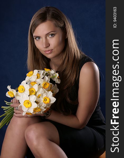 Portrait of the beautiful girl with a bouquet colour, it is photographed on a dark blue background. Portrait of the beautiful girl with a bouquet colour, it is photographed on a dark blue background