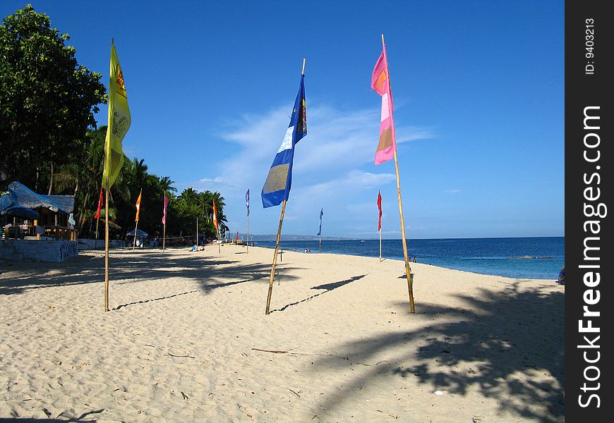 Photo of a beach with white sand and multi-colored flags. Photo of a beach with white sand and multi-colored flags