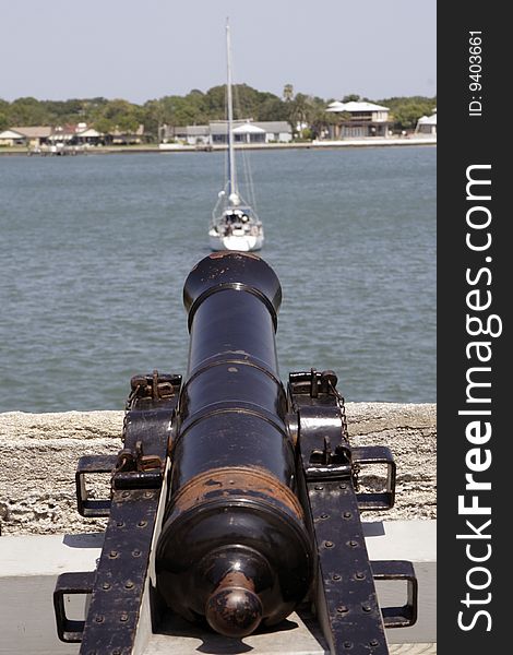 Old Spanish black powder cannon with a sailboat in the background . Old Spanish black powder cannon with a sailboat in the background .