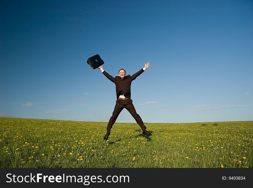 Jumping Businessman in meadow - green grass and blue sky. Jumping Businessman in meadow - green grass and blue sky