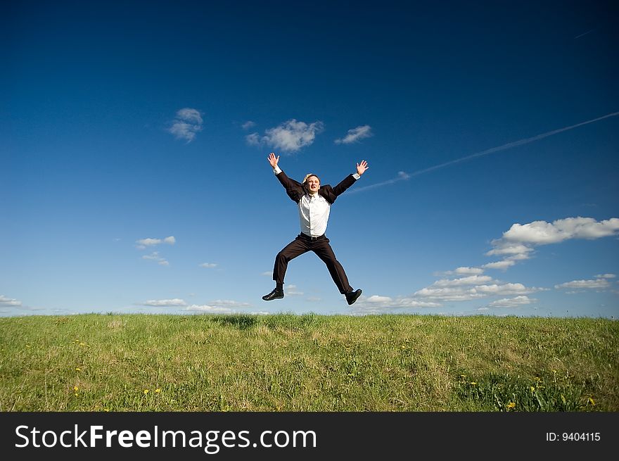 Jumping Businessman in meadow - green grass and blue sky. Jumping Businessman in meadow - green grass and blue sky