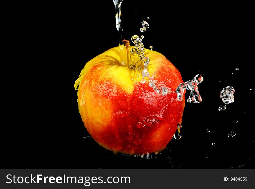 Fresh water splash on a red apple on black background