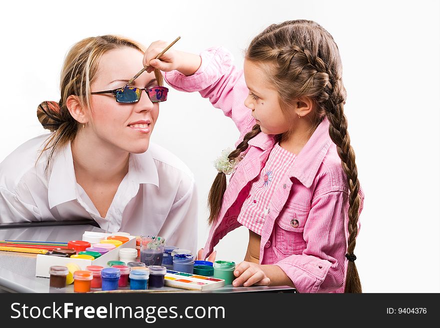 Adorable little girl painting mother's glasses. Adorable little girl painting mother's glasses