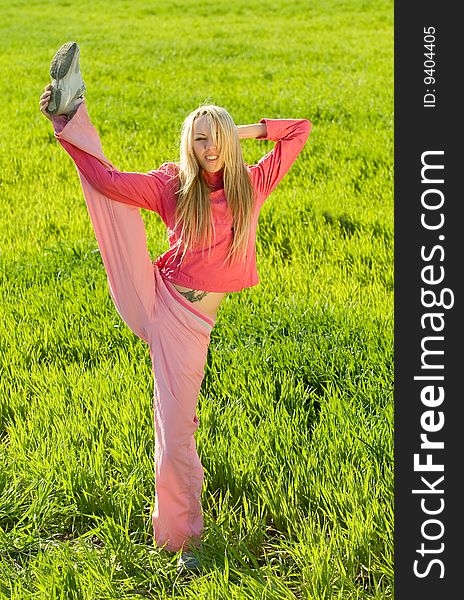 Beautiful young woman exercising on green medow