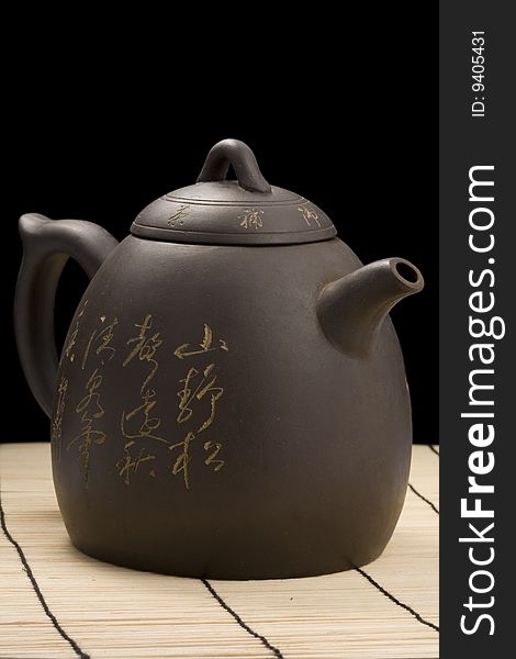 Teapot on mat with clipping path over black background