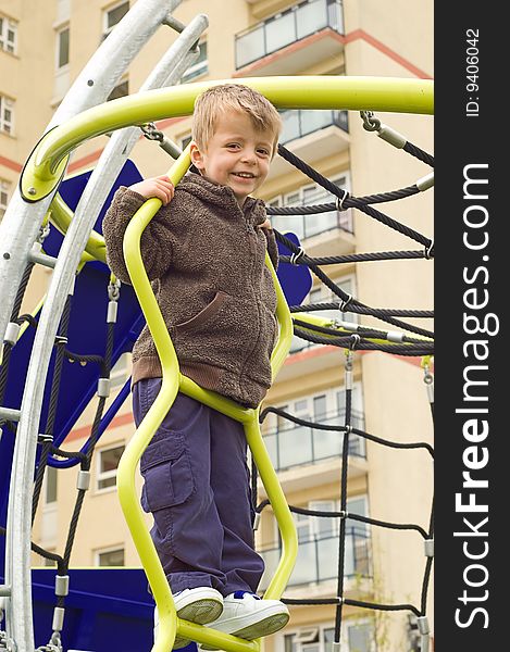 Toddler on climbing frame against an urban background.